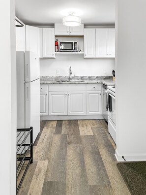 A modern kitchen with white cabinetry, a stainless steel microwave, and a built-in oven. - 2 BR Retreat - 8 Min to Broadway - Free Parking - Close to Everything  - A (Nashville)