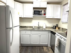 A kitchen with white cabinets, a stainless steel sink, a microwave, and a dishwasher.