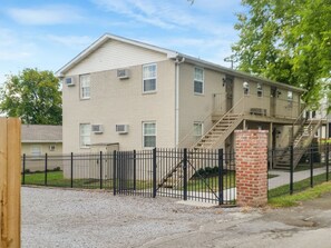 A multi-story residential building with a brick entrance and a metal fence.