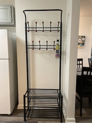 Cozy room with a functional design, featuring a coat rack and a refrigerator.