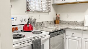 Cocina con armarios blancos, estufa Whirlpool y lavavajillas.
