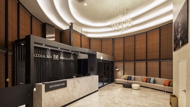 Een hotel receptiegebied met een modern ontwerp, met een receptiebalie, zithoek en een grote kroonluchter.