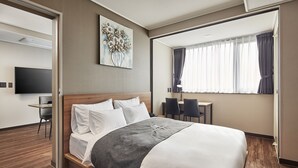 Een hotelkamer met een bed, bureau, stoel, televisie en een raam met gordijnen.