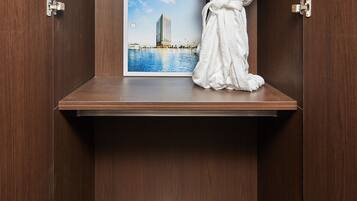 A wooden wardrobe with a robe hanging on the door, a framed picture of a building, and a pair of shoes on the lower shelf.