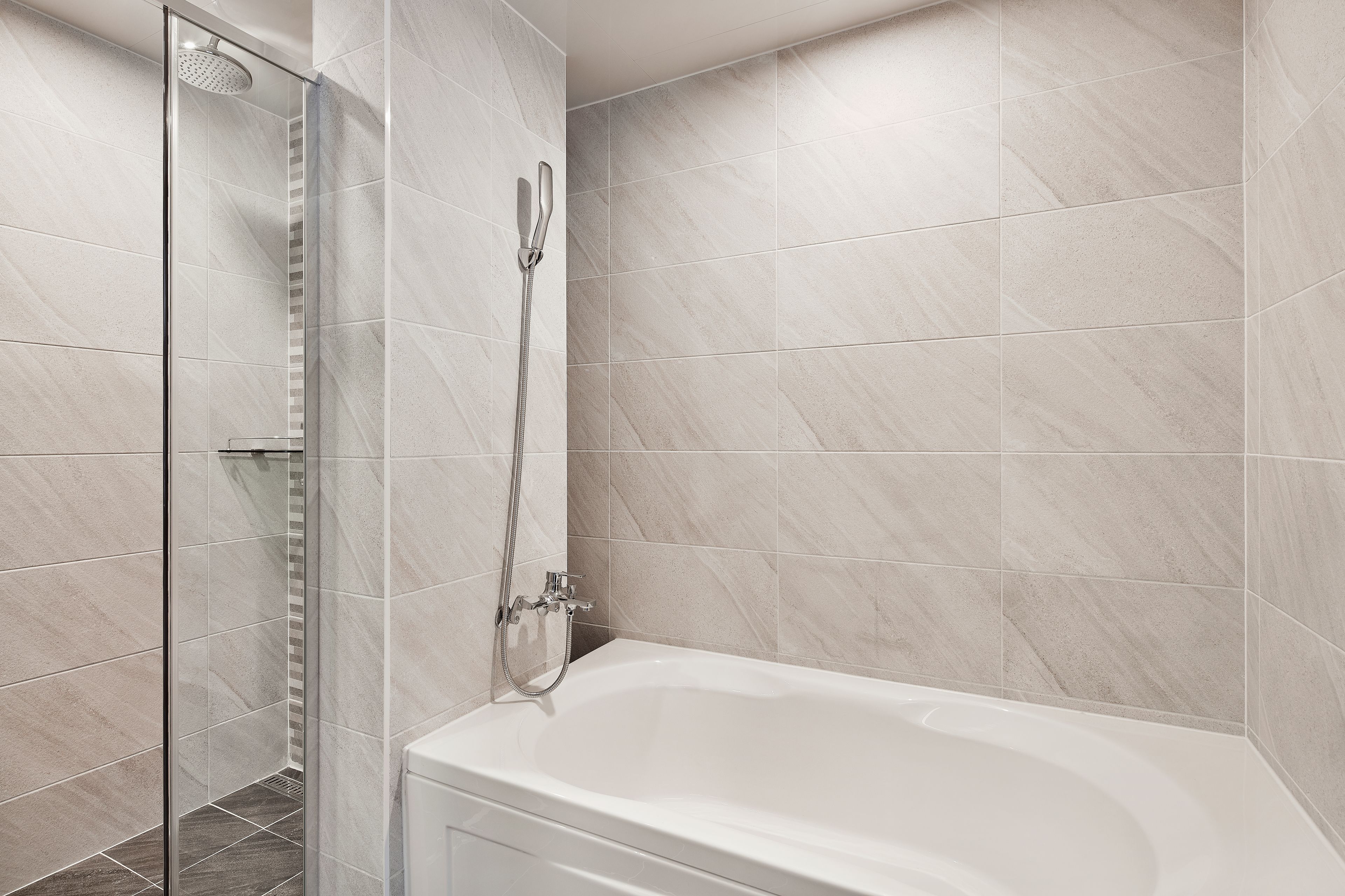 Une salle de bain moderne avec une douche à parois de verre, une baignoire sur pieds et des murs carrelés.