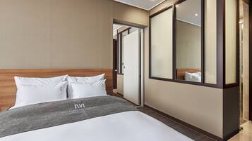 Ein Hotelzimmer mit einem großen Bett, einem Holzkopfstück, einer grauen Tagesdecke und einem großen Spiegel an der Wand.