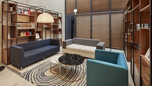 Een moderne woonkamer met een bank, fauteuils, een salontafel en inbouwboekenplanken.