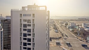 Een hoog hotel met balkons en uitzicht op de haven.