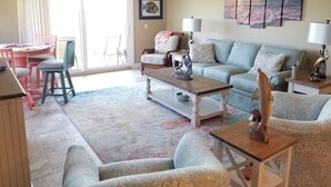 A living room with a sofa, armchairs, a coffee table, and a dining area with a table and chairs. - Summerhouse 101:  Luxury Condo on Beach (St. Augustine)