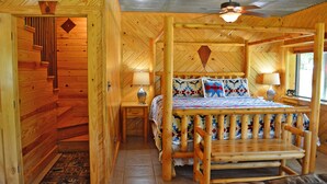 A wooden cabin bedroom with a four-poster bed, two bedside lamps, and a ceiling fan.