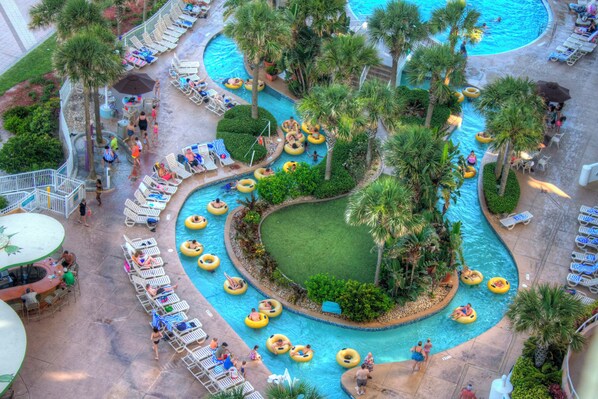 A pool area with multiple water slides, lounge chairs, and palm trees.