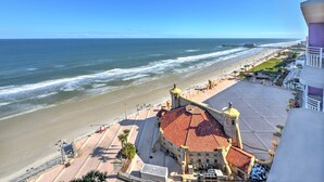 Une vue sur la côte, avec une plage, une promenade et un bâtiment historique surmonté d’un toit en tuiles rouges.