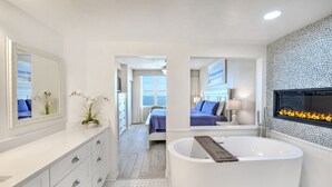 Une salle de bain moderne avec une baignoire sur pieds, un grand miroir et un téléviseur fixé au mur.