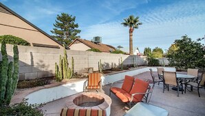 Un espace patio aménagé avec du mobilier d’extérieur, un foyer et des cactus.