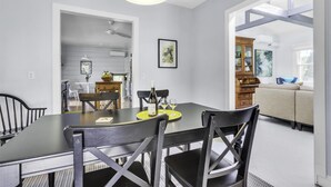 A dining area with a table and chairs, a ceiling fan, and a kitchen in the background. - Wine Country Farmhouse with Hot Tub (Santa Rosa)