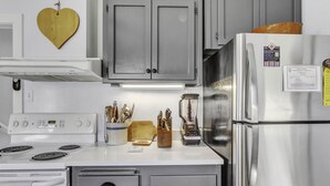 A kitchen with a white stove, grey cabinets, and a stainless steel refrigerator. - Wine Country Farmhouse with Hot Tub (Santa Rosa)