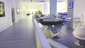 Un vestíbulo moderno con una larga recepción, zona de estar y un bar.