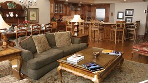 Amplia sala de estar con sofá, mesa de centro y comedor con muebles de madera y una lámpara de araña.