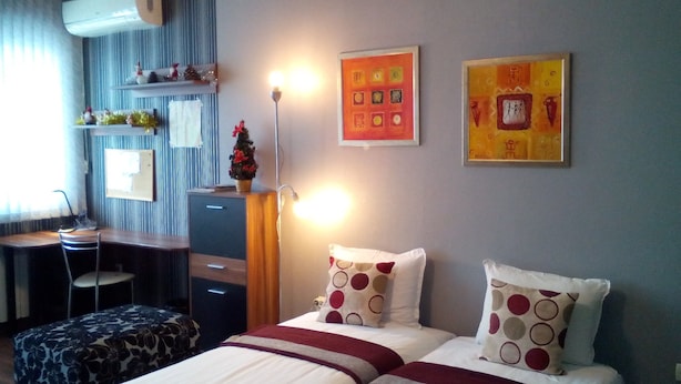 A hotel room with two beds, a desk, a chair, and a small Christmas tree. - Greek Rooms in the City Center (Sofia)