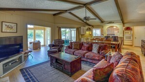 A spacious living room with a large TV, comfortable seating, and a ceiling fan.