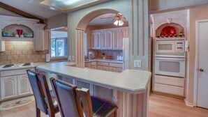 A kitchen with a central island, wooden cabinets, a microwave, and a stove.