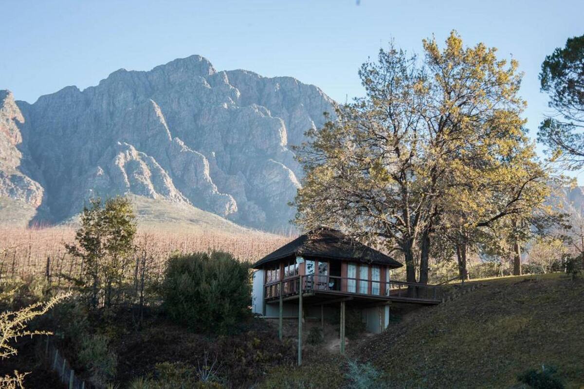 Una cabaña rústica con balcón, rodeada de árboles y montañas.