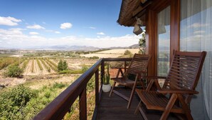 A wooden deck with two wooden chairs overlooking a vineyard and distant mountains. - Tulbagh Mountain Manor (Tulbagh)