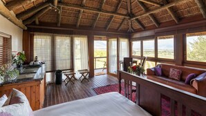 A spacious room with a wooden ceiling, large windows, a bed, a sofa, and a small table. - Tulbagh Mountain Manor (Tulbagh)