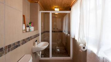 Un bagno con doccia, WC e lavandino.