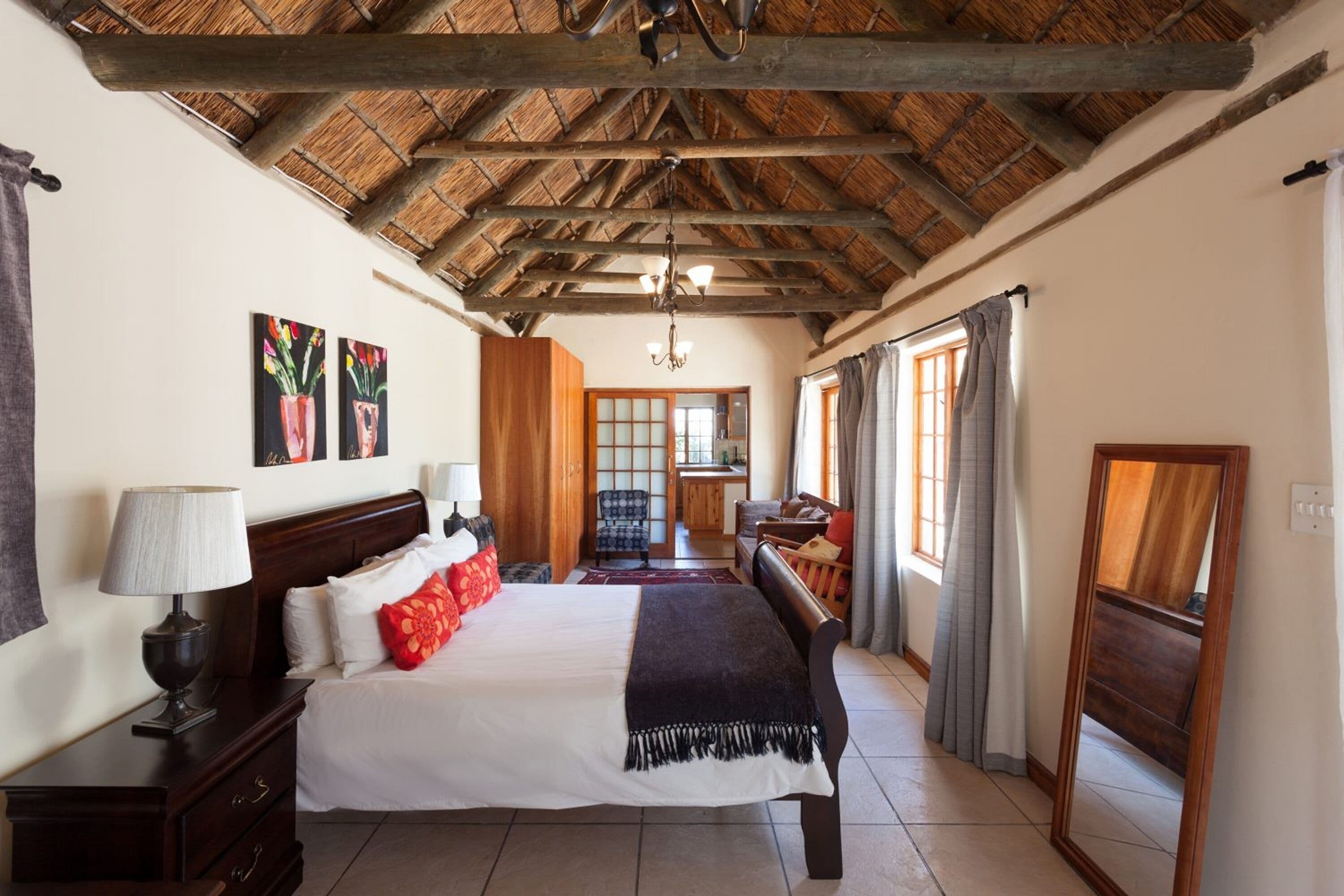 Un dormitorio amplio con una cama grande, cabecera de madera y techo de paja.