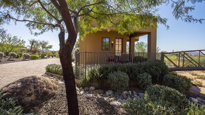 A single-story house with a covered porch, surrounded by a landscaped garden with rocks and shrubs. - Private with Mountain Views and City Lights (Scottsdale)