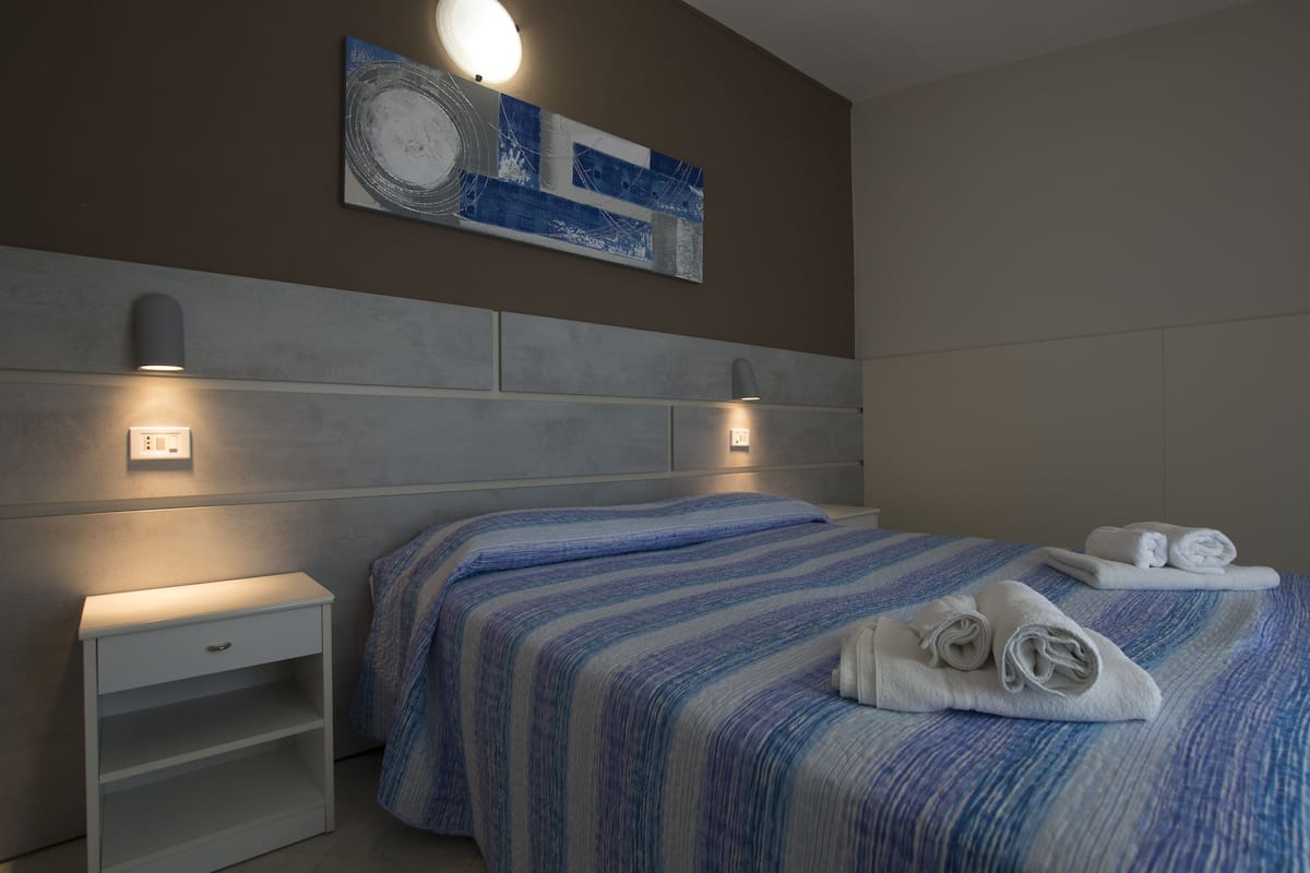 Une chambre d’hôtel moderne avec un grand lit, deux tables de chevet et une œuvre d’art accrochée au mur.