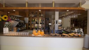 A bar area with a variety of beverages, including bottles and glasses, and a selection of food items. - Hotel San Domenico (Cervia)