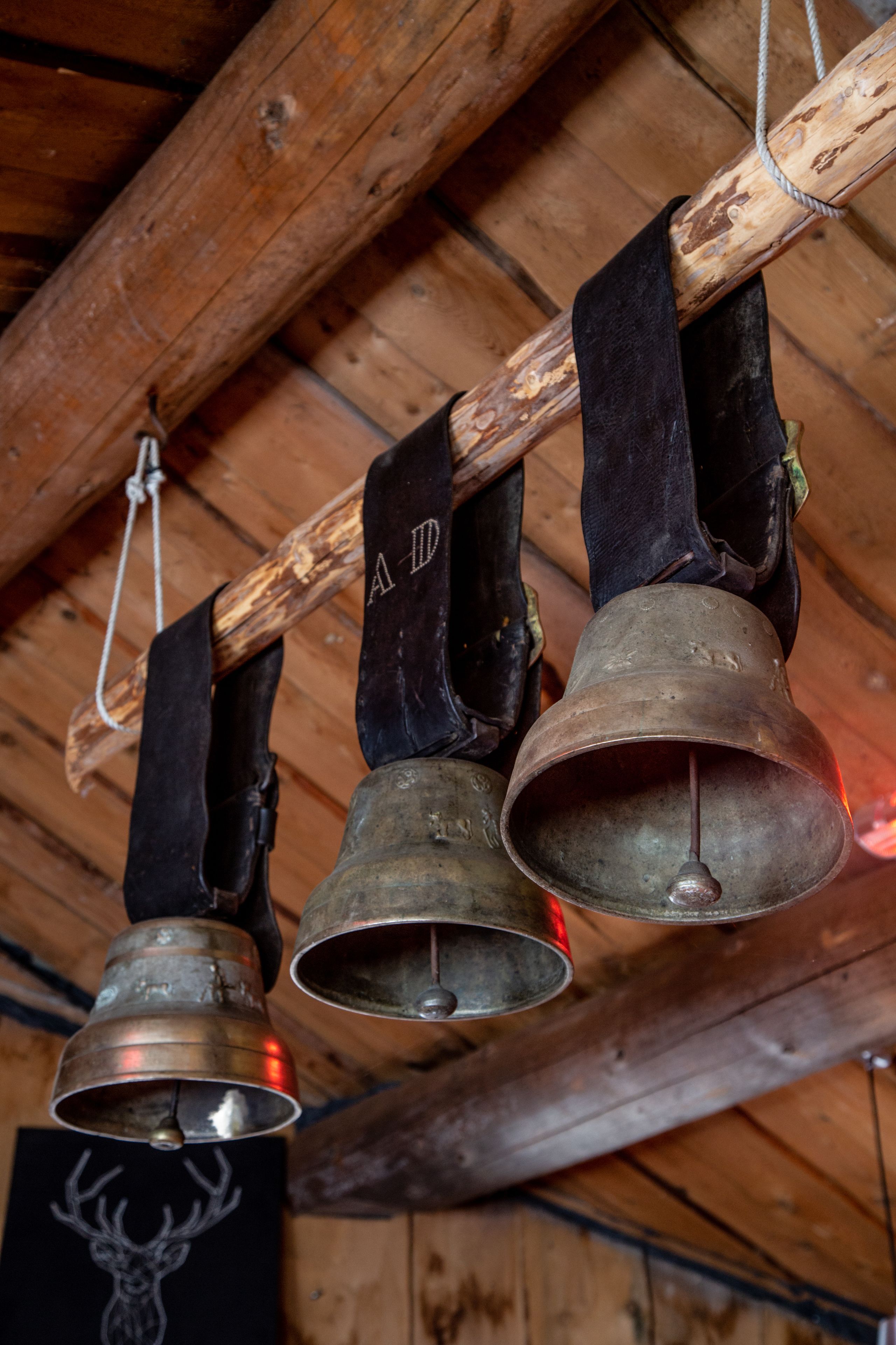 Three bells hanging from a wooden beam.