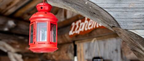 Un farol rojo colgado de una viga de madera.