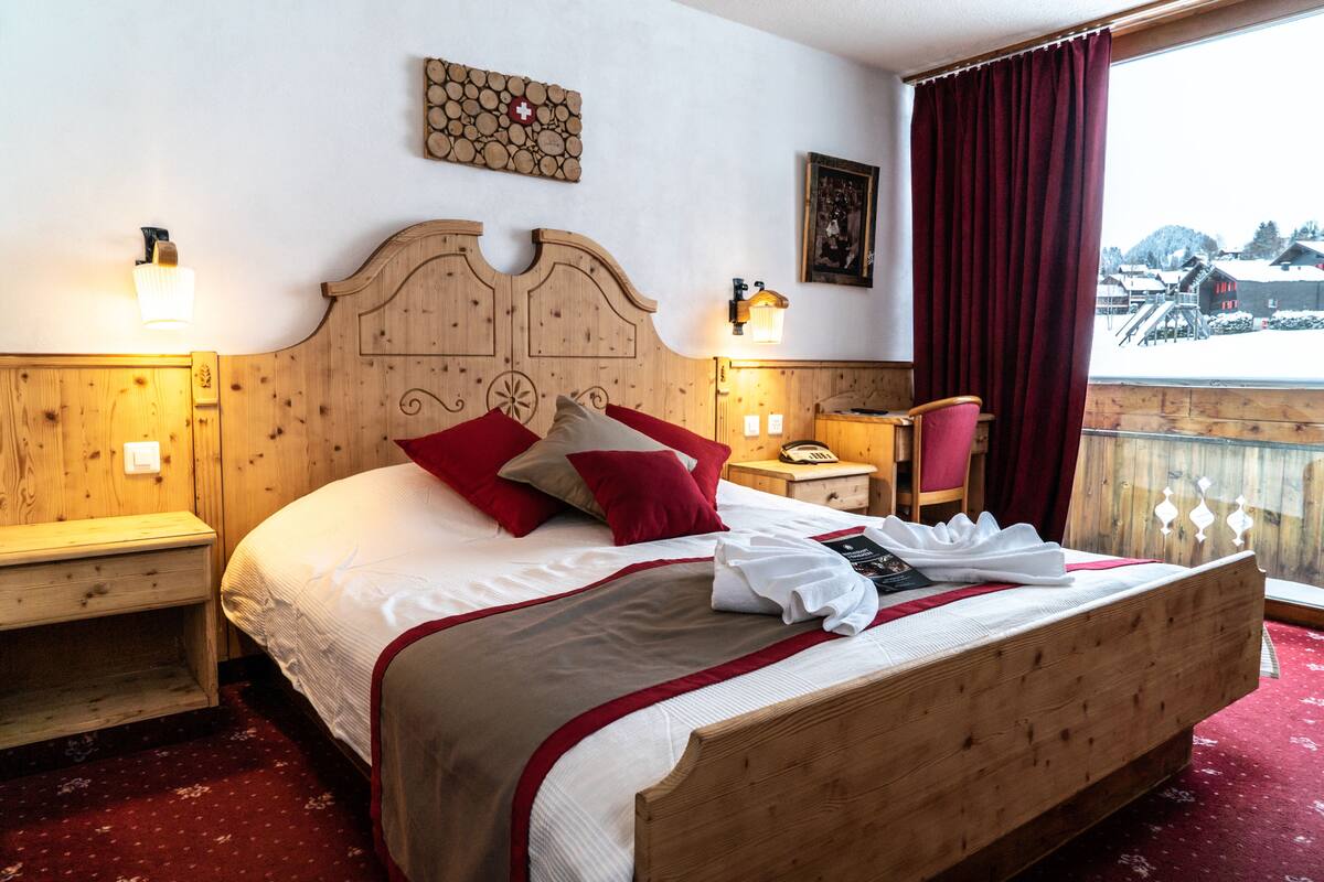 Una cama de madera con almohadas rojas y grises, un cabecero de madera y una cortina roja.