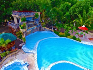 Una gran piscina al aire libre con una estructura de piedra y un letrero que indica un hotel.