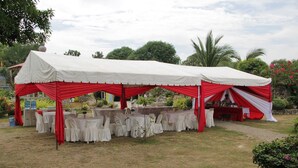 A tented outdoor event space with tables and chairs, surrounded by greenery. - Punta Aguila Resort & Hotel (San Juan)