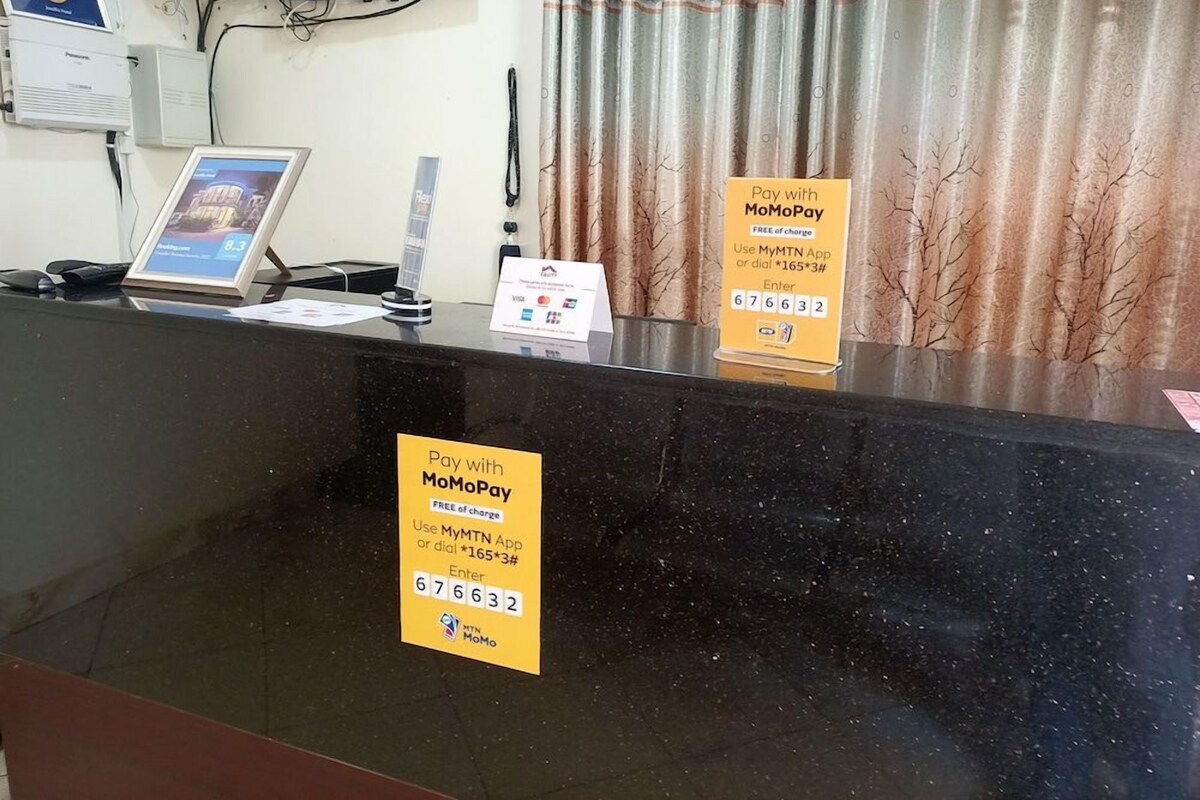 Ein Empfangstresen mit schwarzer Arbeitsfläche, einem Laptop, einem Telefon und zwei gelben Schildern zur Werbung für MoMoPay Zahlungsmöglichkeiten.