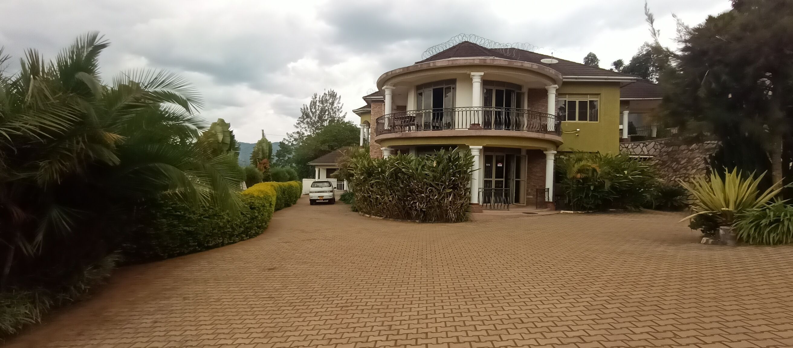 A large, two-story house with a curved balcony and a paved driveway.