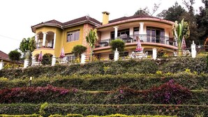 Una casa grande de dos pisos con un balcón curvo y un jardín delantero.
