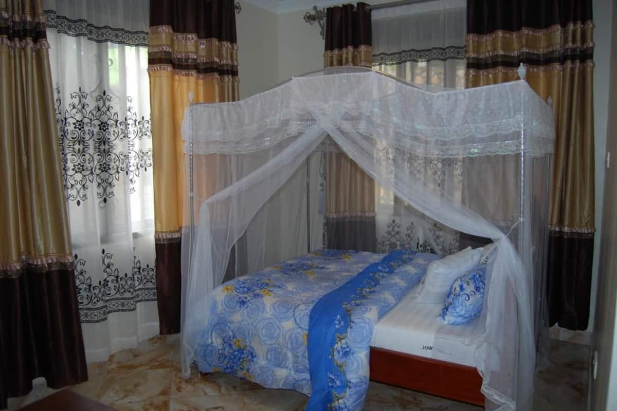 A bedroom with a canopy bed, curtains, and a patterned bedspread.