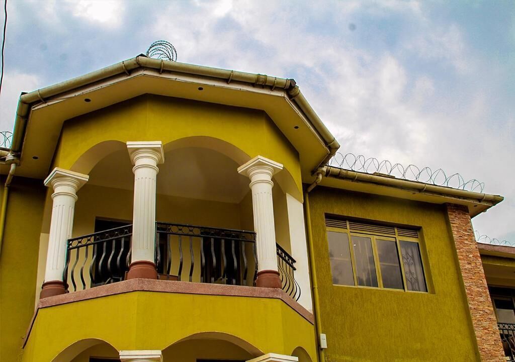 Un bâtiment jaune doté d’un balcon, de colonnes blanches et d’une balustrade à barreaux.