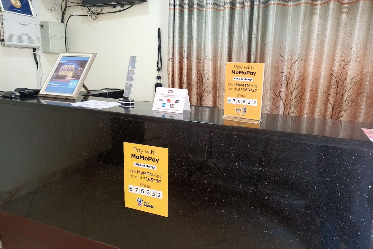 A reception desk with MoMoPay payment options, a Panasonic air conditioner, and a television mounted on the wall.