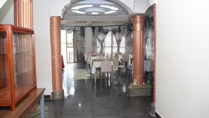 Un vestíbulo de hotel con suelo de mármol, un mostrador de recepción y una zona de estar con mesas y sillas.