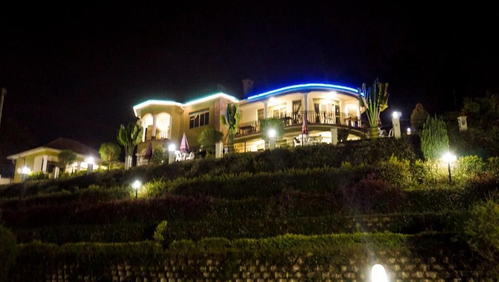 A large, multi-story building with a curved roofline, illuminated by exterior lighting.