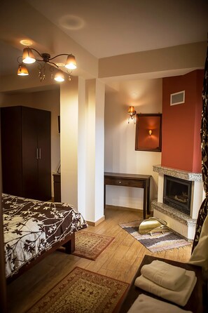 Une chambre à coucher avec un lit, un bureau, une cheminée et une armoire.