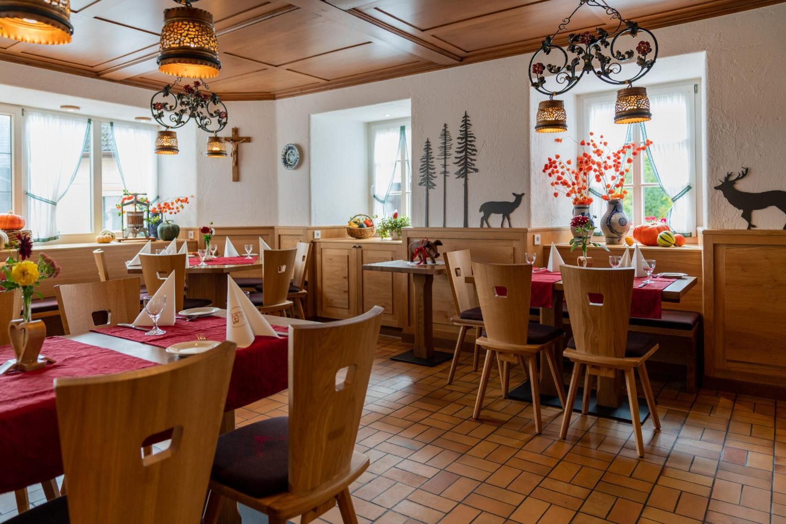 A restaurant with wooden furniture, red tablecloths, and decorative wall art.