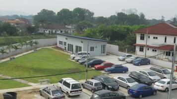 A parking lot with several cars, a small building, and a grassy area.
