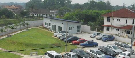 A parking lot with several cars, a small building, and a grassy area.